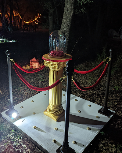 Gold column supporting glass display dome, enclosed by gold stanchions with red velvet ropes.